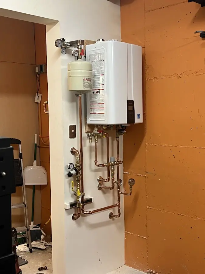 Plumbing technician inspecting water heater connections in Iowa Falls